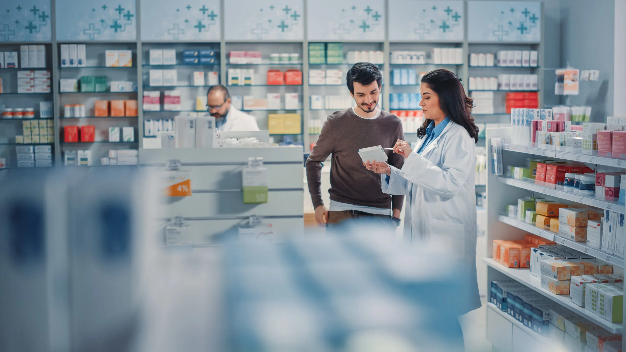 Apothekerin und Kunde sehen gemeinsam auf ein Tablet